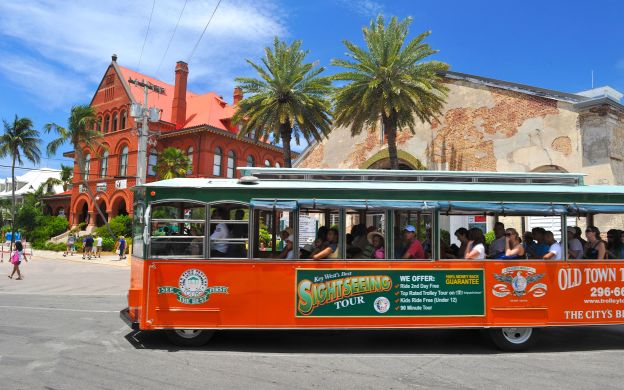 Vibrant orange Key West Hop-On, Hop-Off Trolley gracefully moving through the streets, showcasing the essence of island exploration.